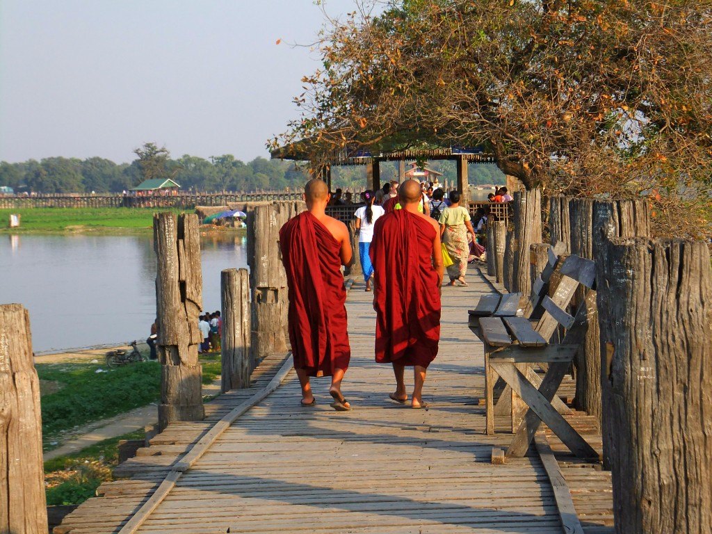 Två munkar promererar över U Bein Bridge i Amarapura, Burma i solnedgången - favoritländer